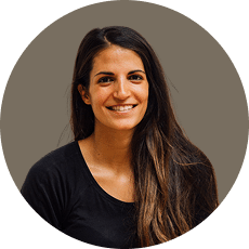 Smiling person with long dark hair wearing a black shirt against a neutral background.